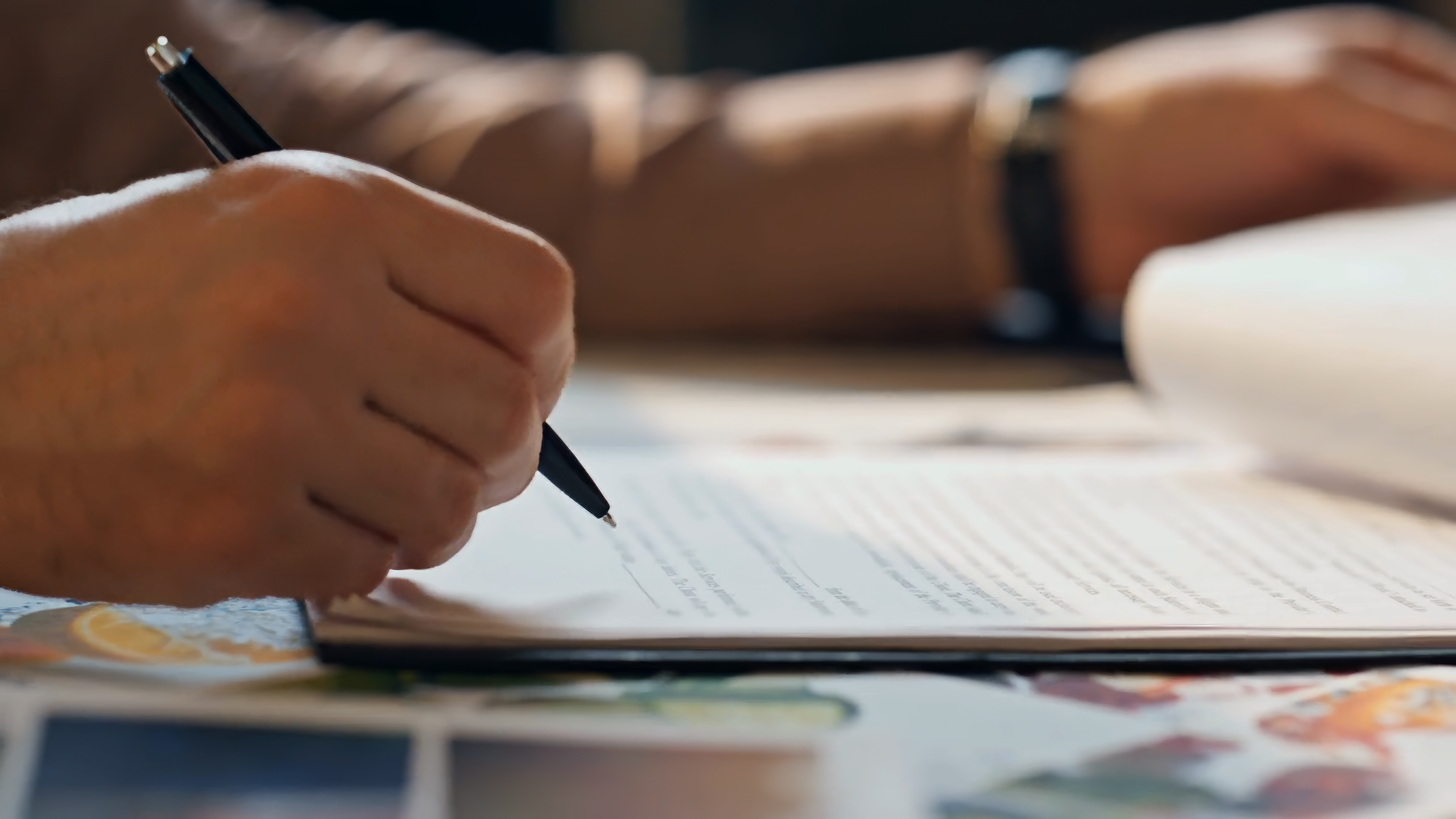 Closeup of Businessperson Hand Signing Contract At Office Table