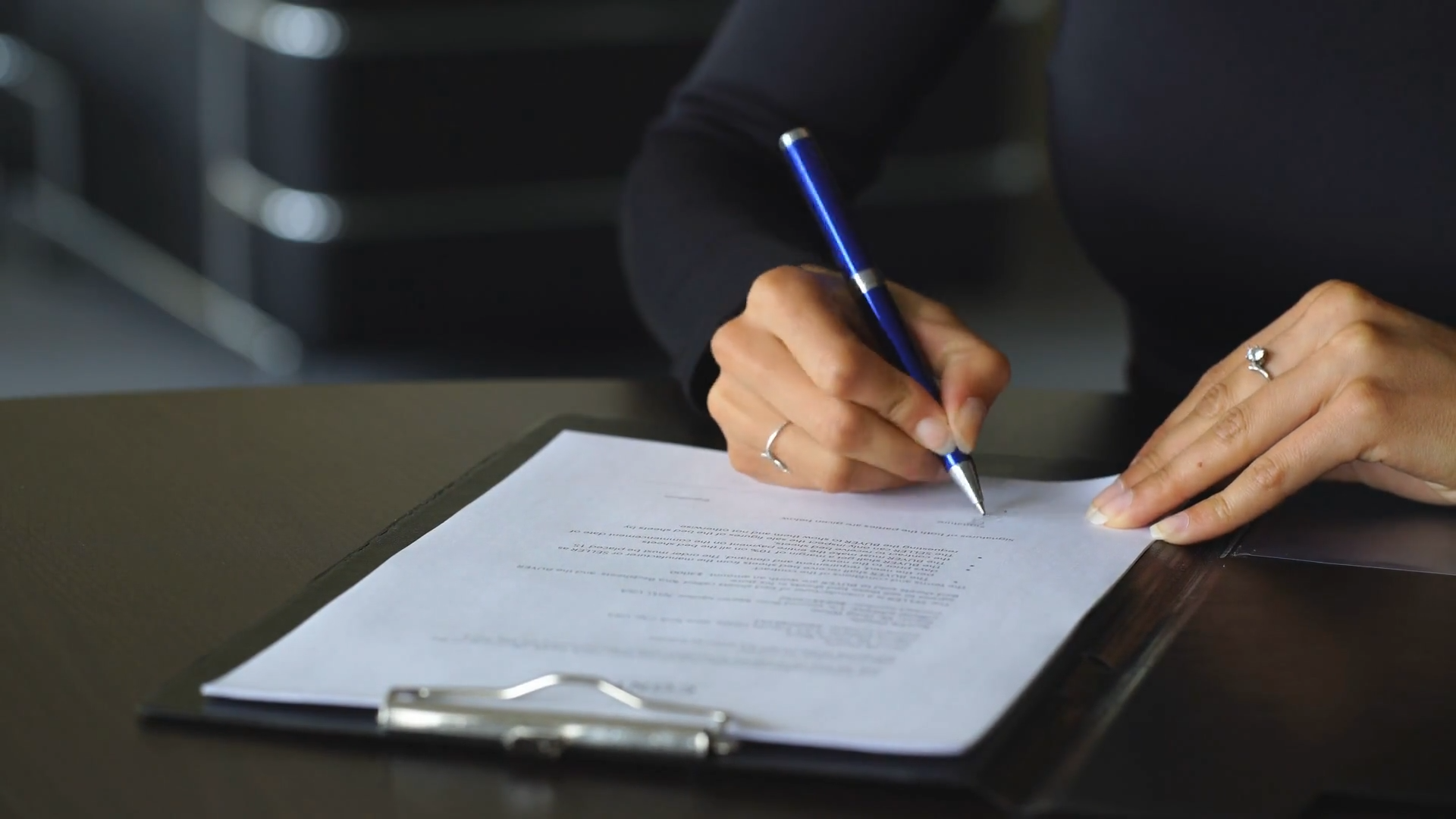 womans hand with pen signing document close up